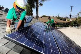 Two people in green installing solar panels