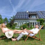 Mid,Adult,Couple,In,Deckchairs,In,Garden,Of,Solar,Paneled